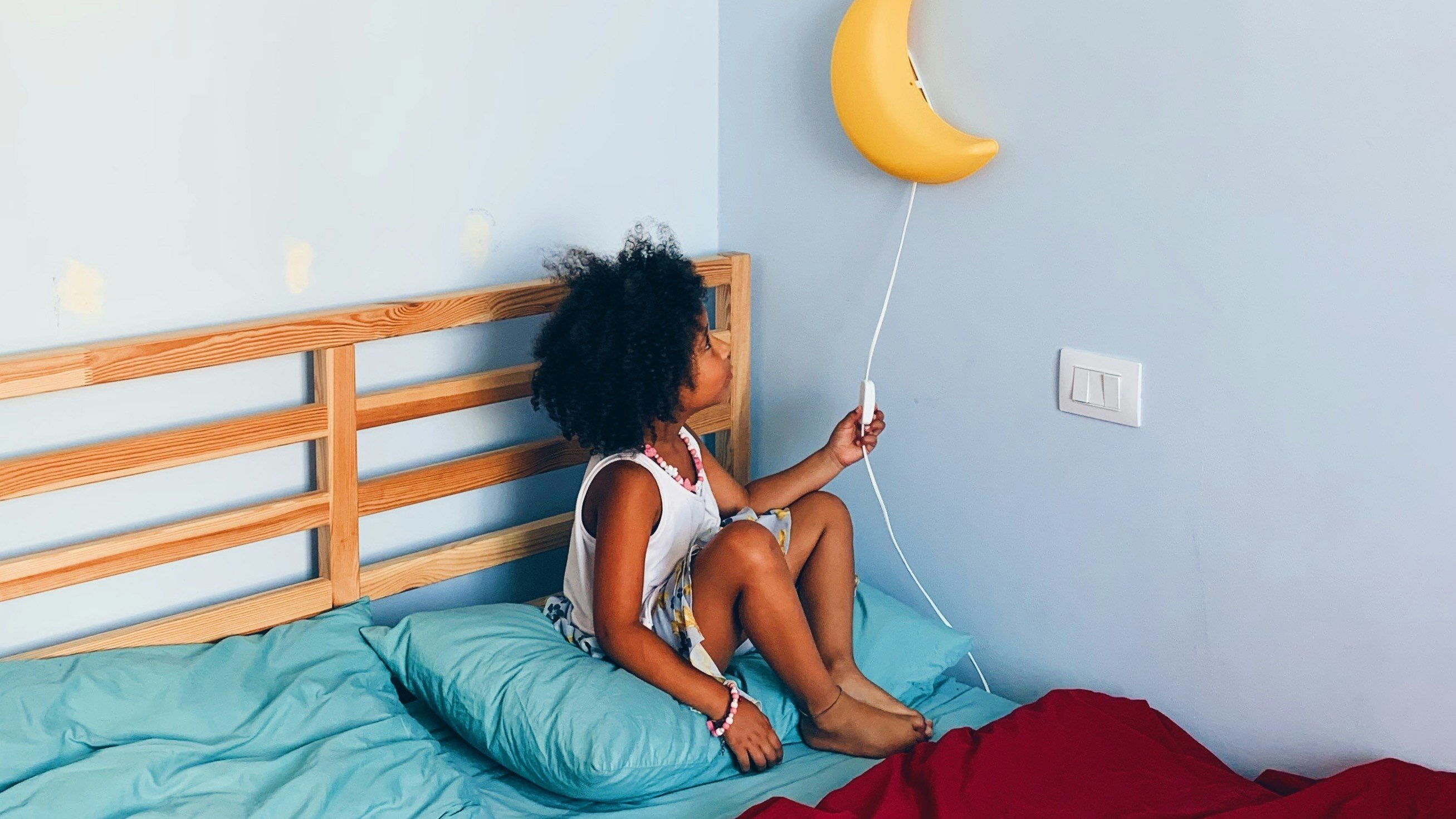 Enfant de 4 ans qui prépare le coucher avec une lampe lune, rituel du soir dans sa chambre mais qui ne veut pas vraiment aller se coucher