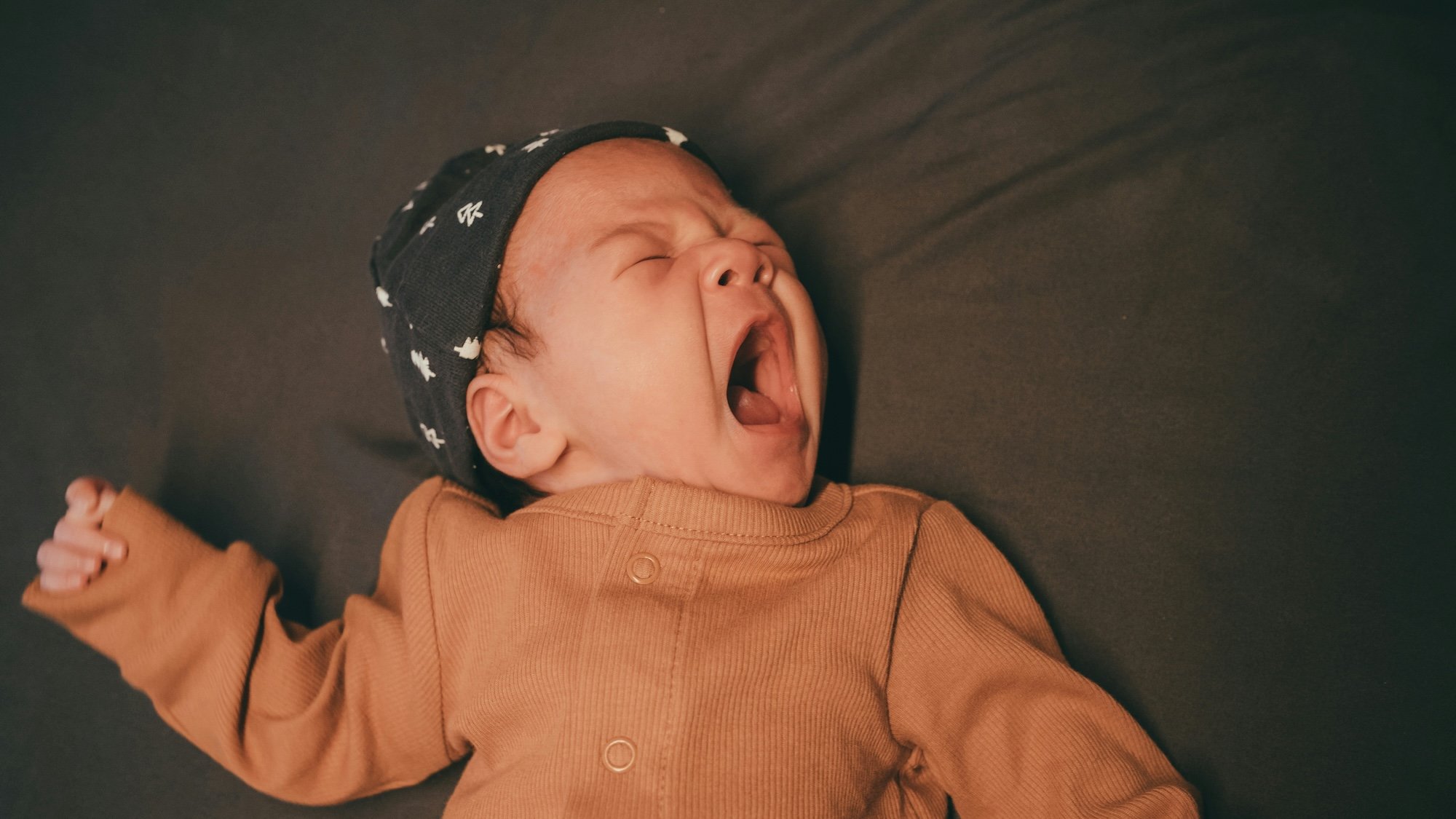 Bébé fatigué qui baille, signe de sommeil et de coucher difficile le soir.