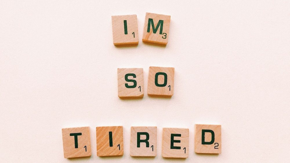 Lettres de Scrabble formant "I am so tired" posées sur une table, illustration de la fatigue des parents et des rdv sommeil gratuits à Toulouse