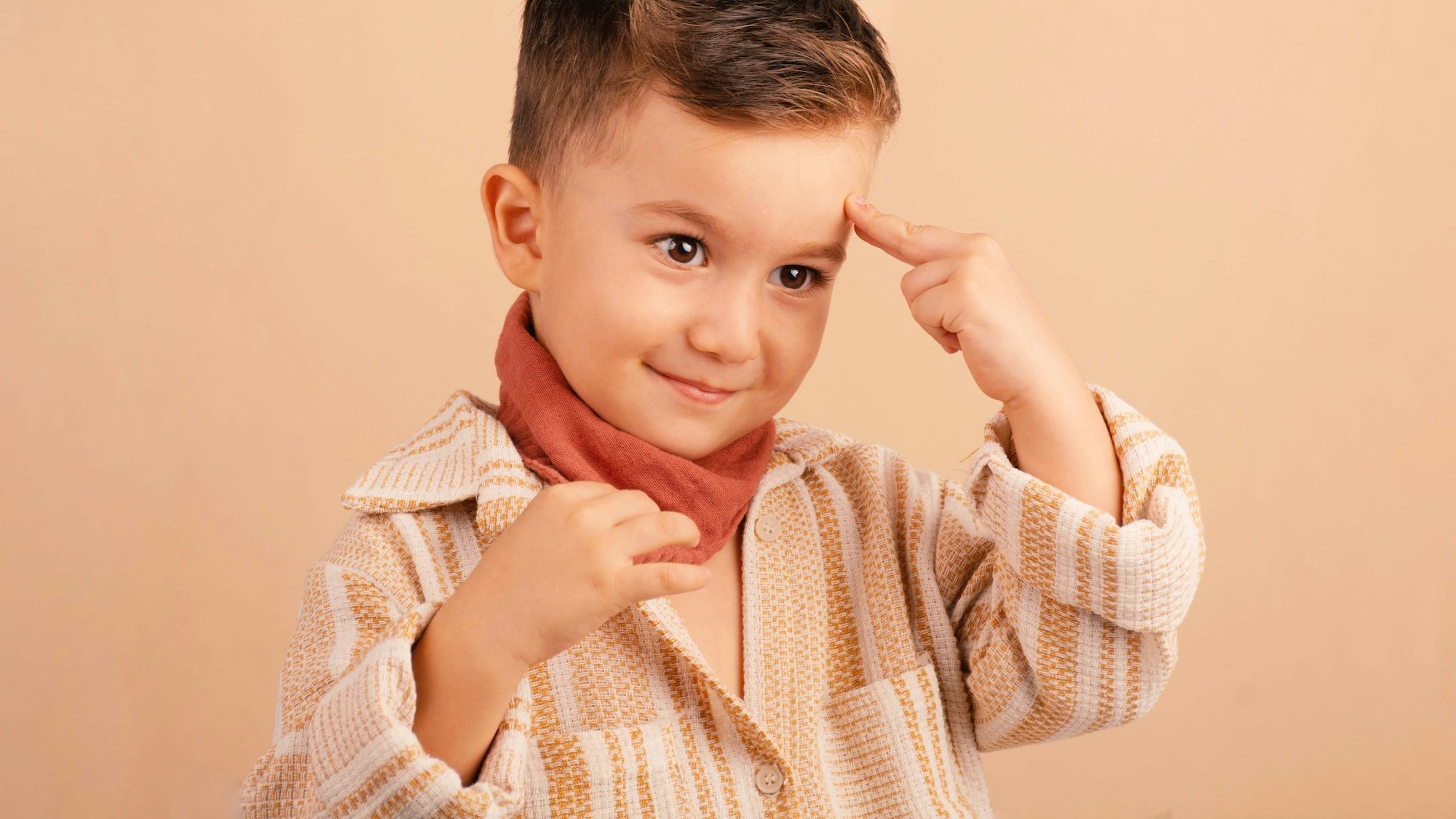 Enfant de 3 ans pointant son index sur son front comme signe de réflexion intense