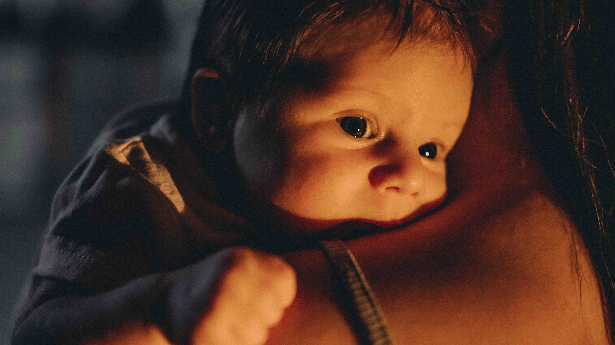 Nourrisson fatigué porté contre sa mère – image évoquant les nuits hachées et les besoins de proximité des bébés