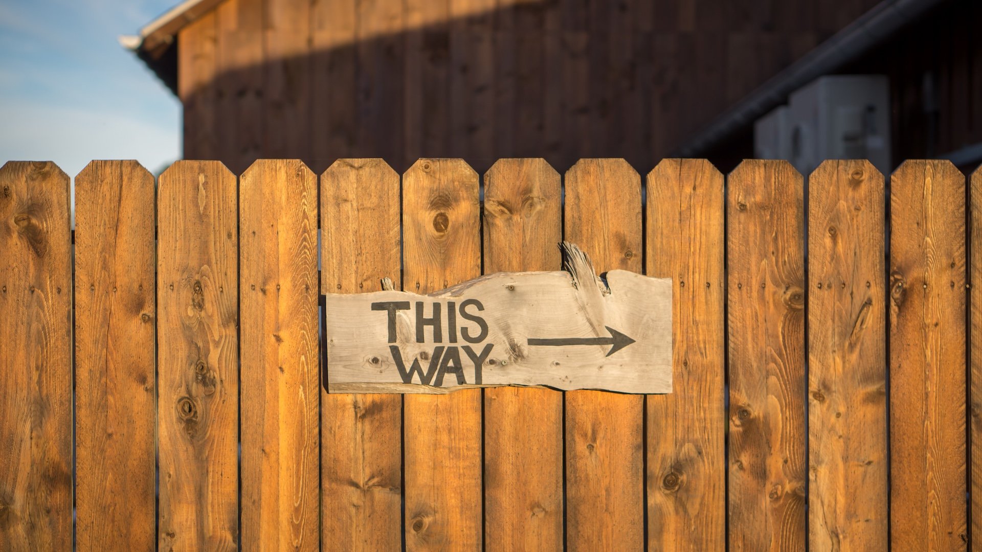 Panneau en bois “This Way” indiquant la bonne direction – un premier pas rassurant vers la compréhension et l'amélioration du sommeil de votre enfant grâce à une consultation personnalisée.