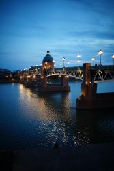 Vue nocturne du Pont Neuf et du dôme de La Grave à Toulouse, illuminés dans la nuit, reflet sur la Garonne, symbole de la région toulousaine.