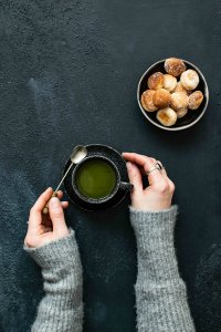 Vue du dessus de mains féminines tenant une tasse de café, avec un bol de chouquettes à côté – moment cocooning au Pompon sur la Daronne à Toulouse.