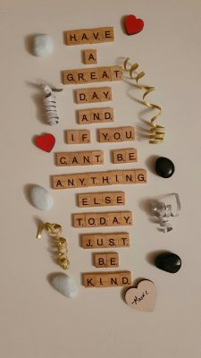 Lettres de Scrabble formant le message "have a great day and if you can't be anything else today, just be kind", entourées de cœurs en bois rouges et d'éléments doux ; un clin d'œil bienveillant pour les parents épuisés, comme Julien et Stéphanie, accompagnés sur le sommeil de leur enfant de 2 ans.