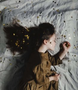 Petite fille dormant paisiblement dans un lit, draps étoilés – illustration d'un coucher serein grâce à l'accompagnement sommeil