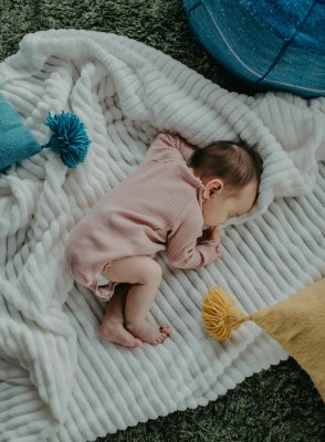 Nourrisson endormi sur une couverture blanche, installé dans un petit coin improvisé pour la sieste en vacances