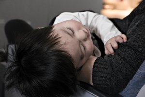 Bébé aux cheveux noirs faisant une sieste paisible dans les bras de sa mère