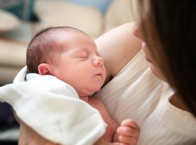 Bébé endormi dans les bras de sa mère montrant un sommeil sécurisé grâce à la présence parentale