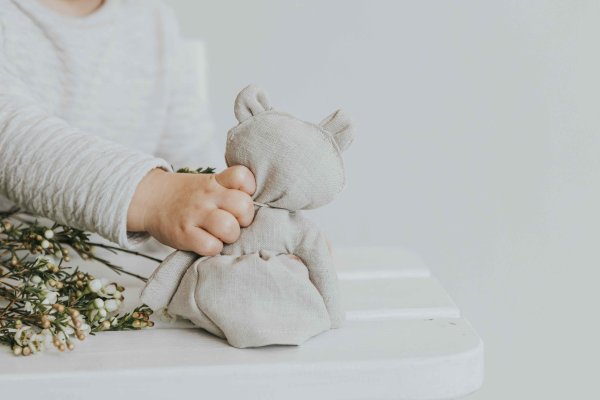 Doudou en lin dans la main d'un enfant de 18 mois, ambiance douce et lumineuse